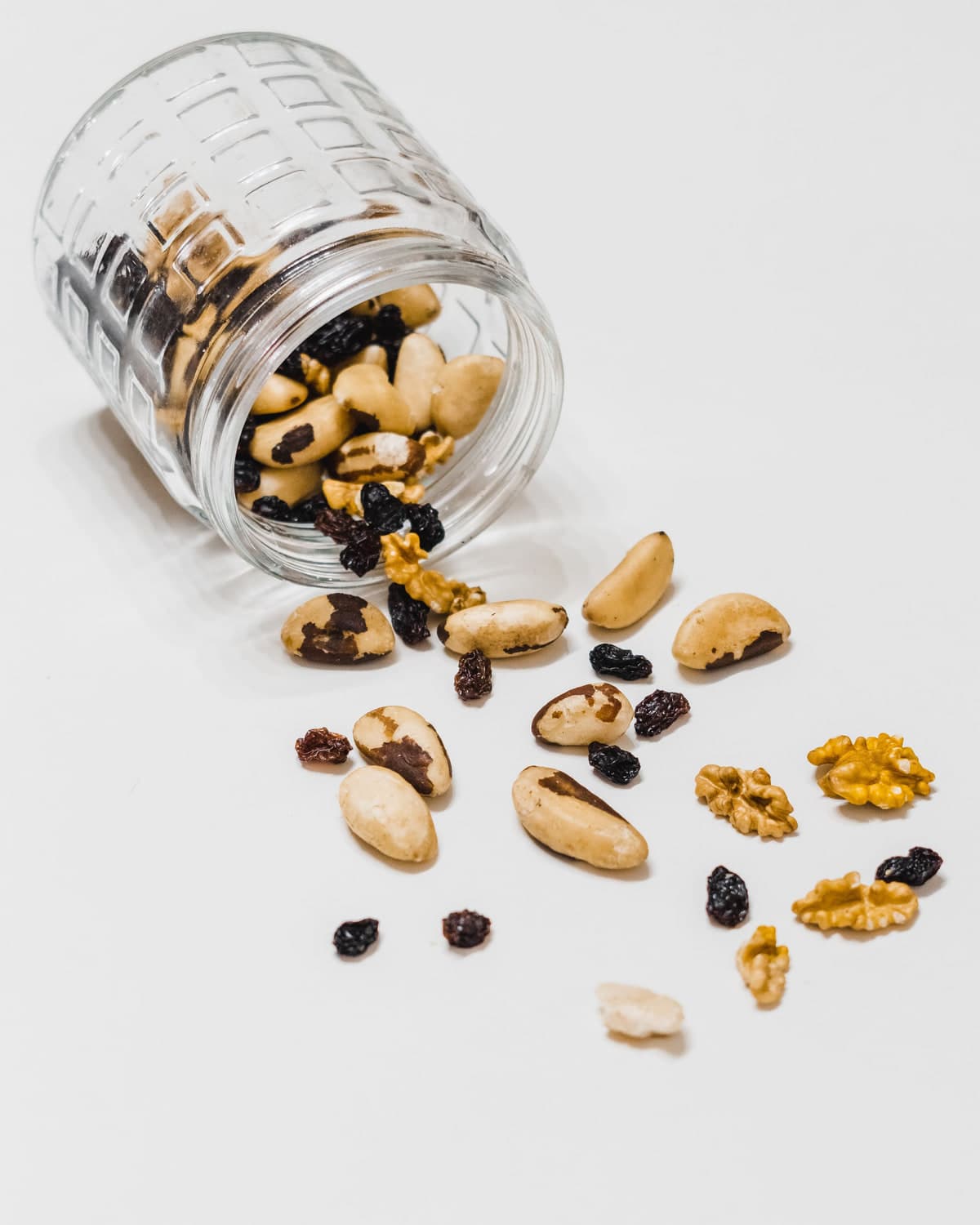 Mixed nuts and raisins spilling from a glass jar