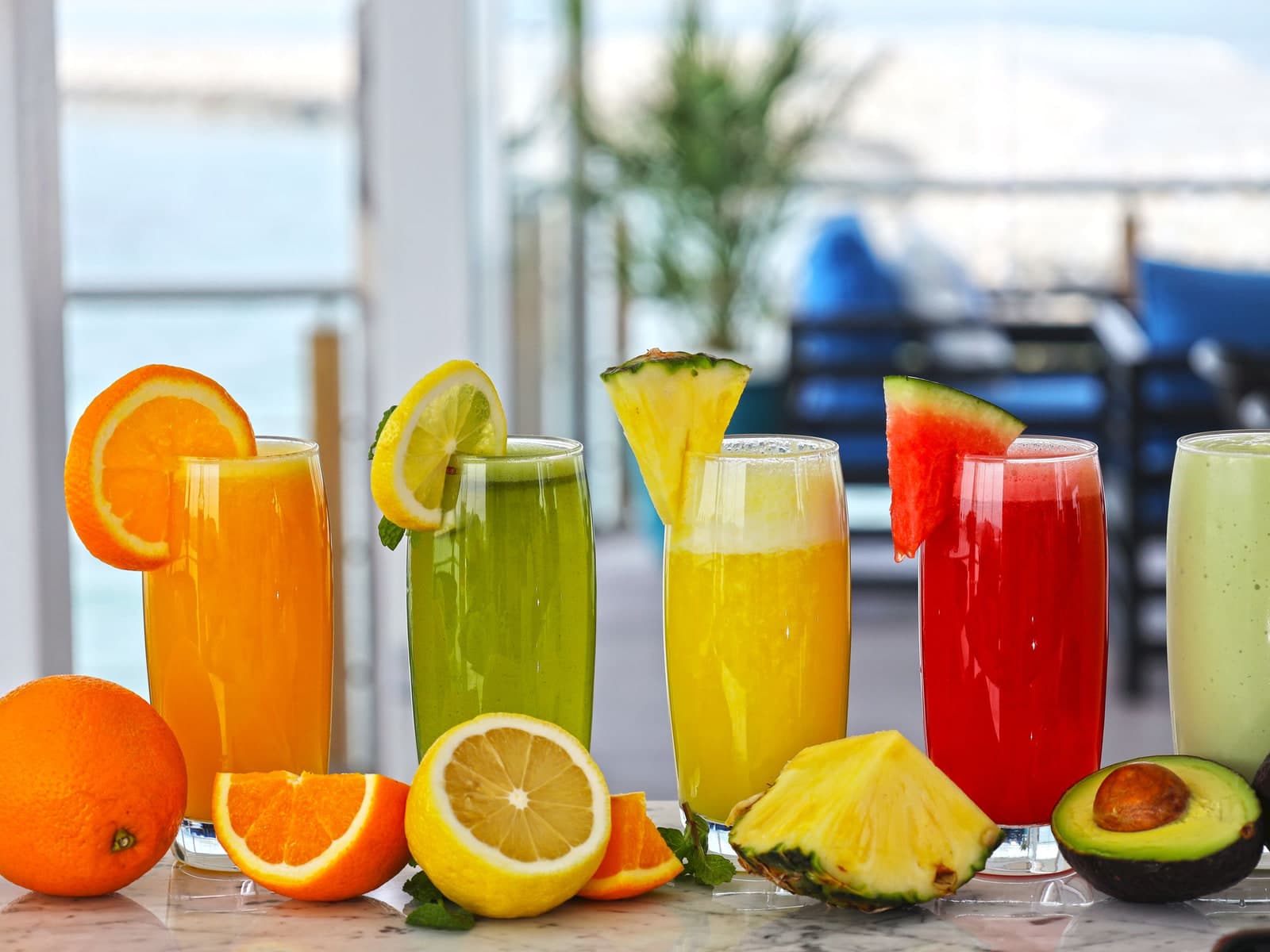 Glasses of fresh juice with cut fruit
