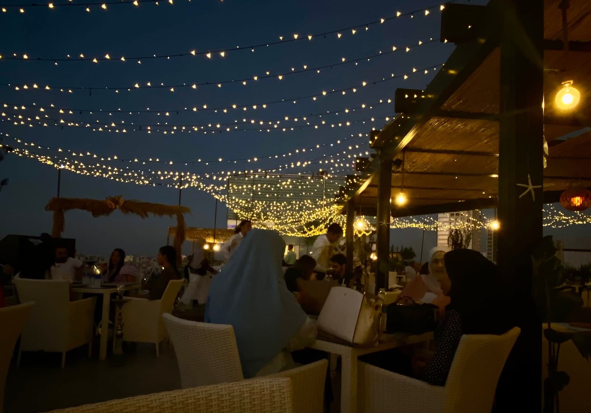 Rooftop tables under string lights at night